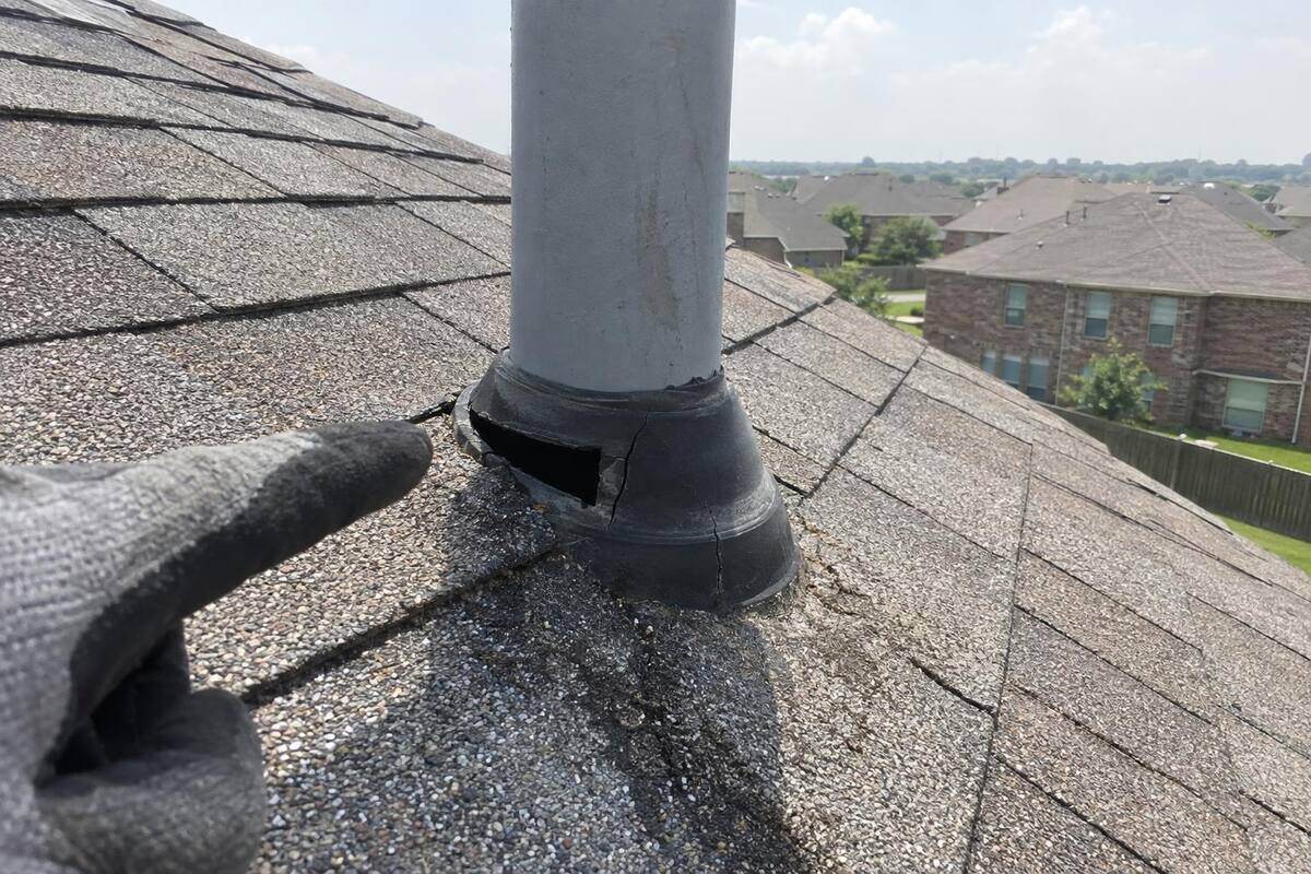 Cracked, sun-split rubber boot around a plumbing vent pipe on a shingle roof