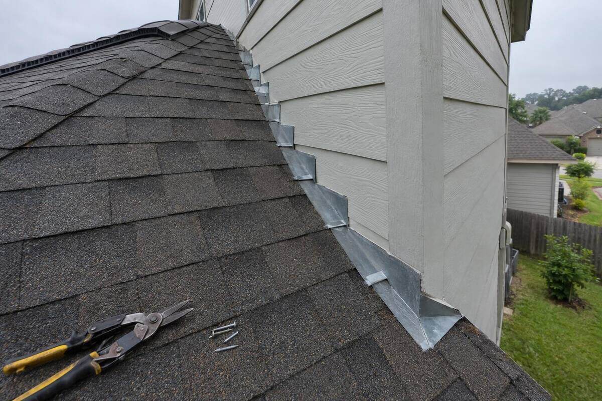 Shingle-over ridge vent along the peak of a roof, with metal step flashing where the roof meets a wall